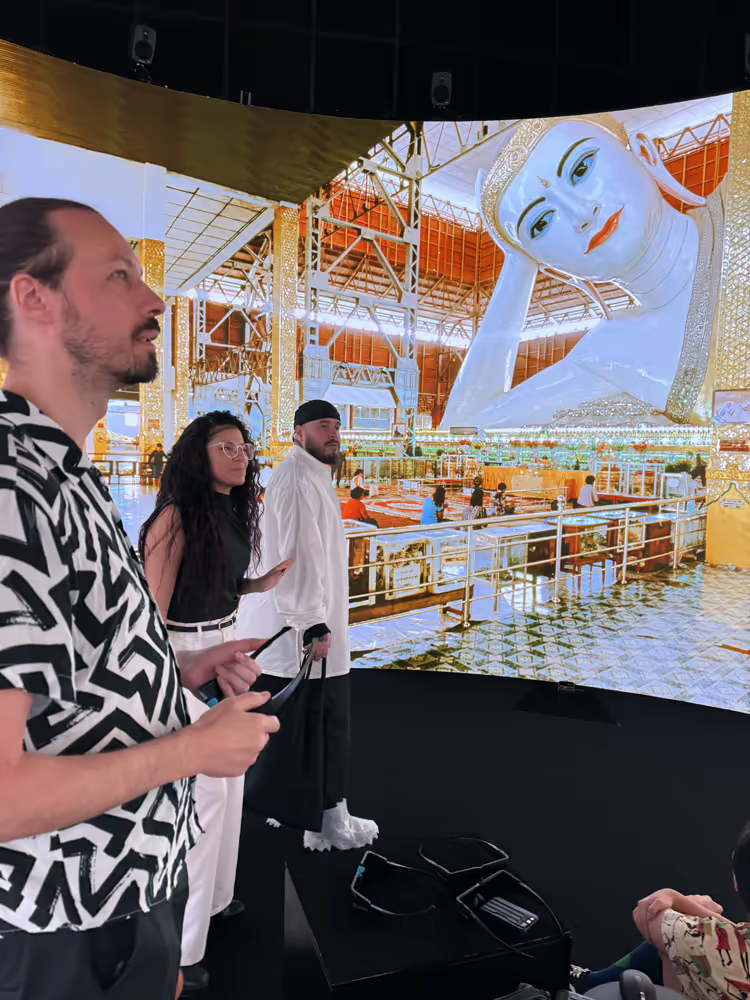 Visitors wearing 3D glasses inside the nVis display, facing a large reclining Buddha panorama.