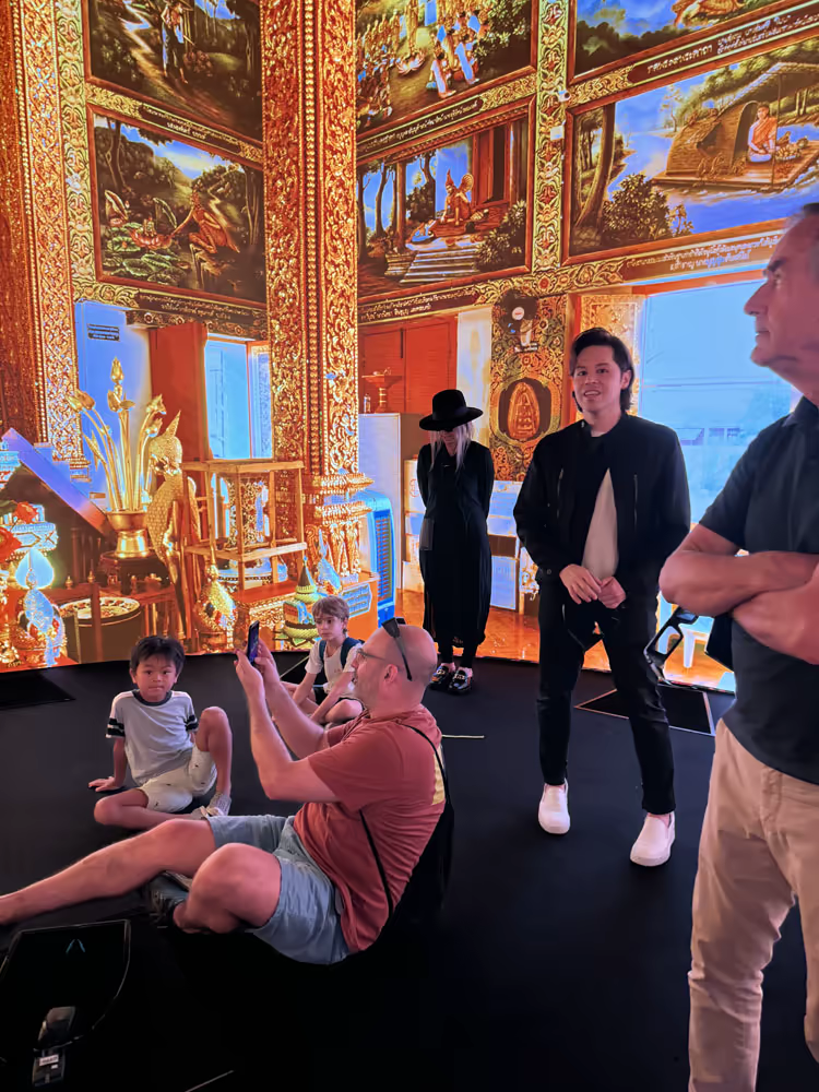 Visitors inside a 360 projection of a richly decorated Buddhist temple interior.