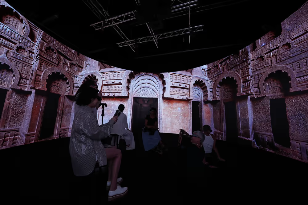 Visitors inside a rock-cut temple panorama displayed across the 360 screen.