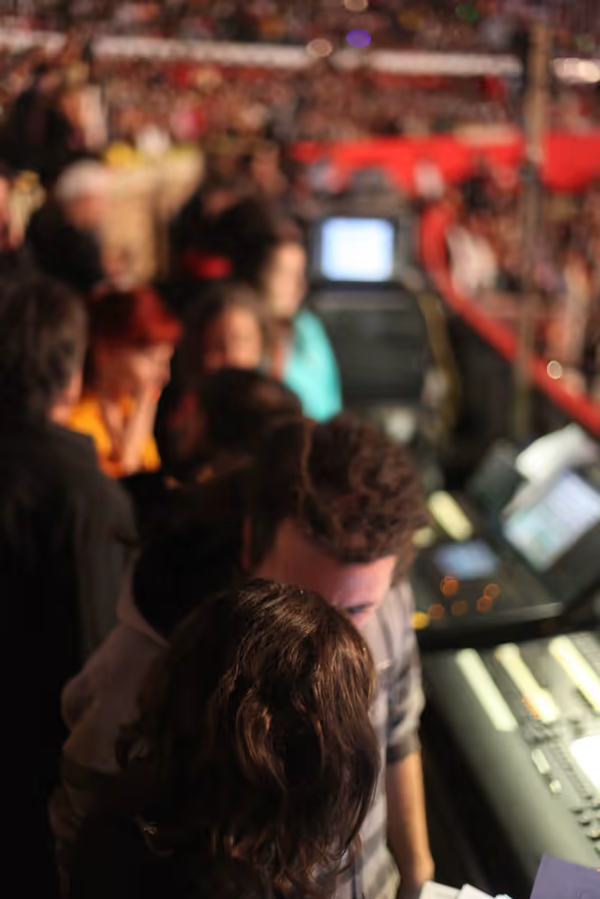 Behind-the-scenes coordination between Alejandro Rodríguez and the technical team, with audience in the background.